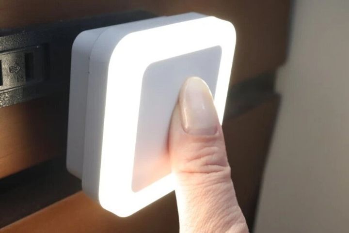 コンセントに挿したナイトライトのセンサーを指で覆い点灯させている