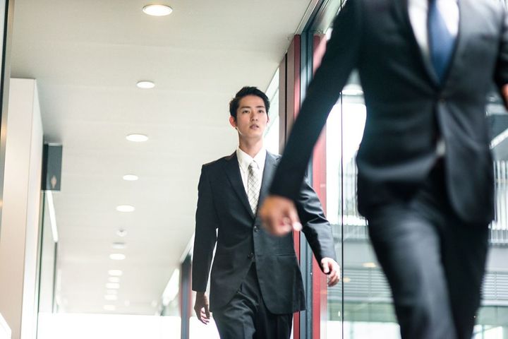 会社の通路を歩く男性