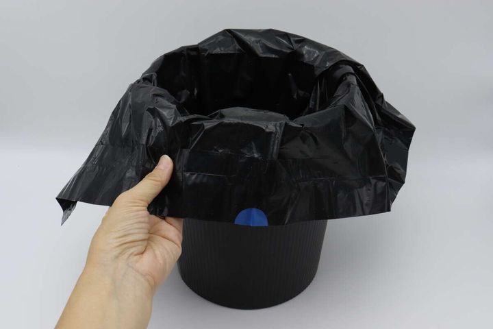 黒いゴミ箱に黒いビニール袋を被せている様子