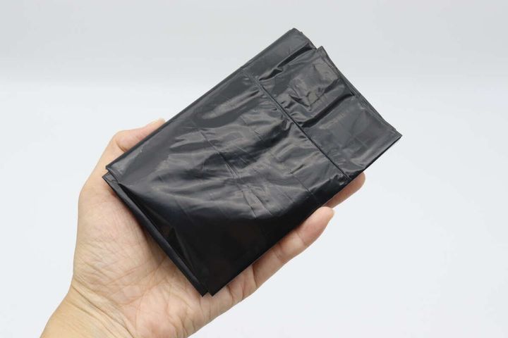女性の手のひらに乗せられた黒く折りたたまれた袋