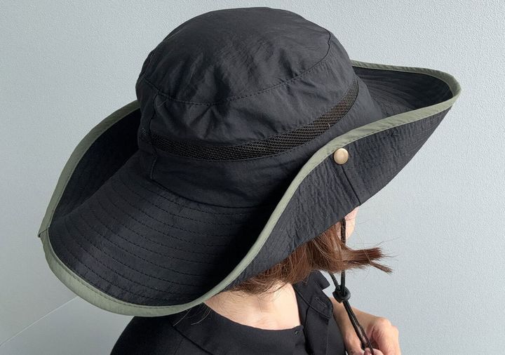 黒いサファリハットを被った女性。つばをスナップボタンで上げた状態。