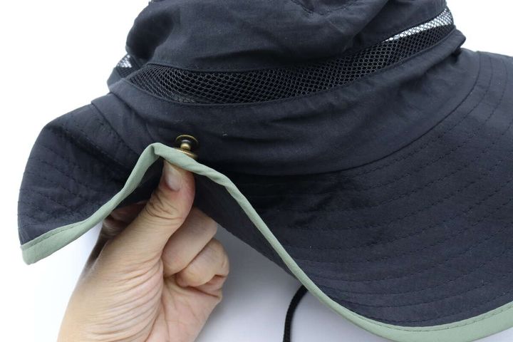 女性の手がサファリハットのつばをスナップボタンで留めている。
