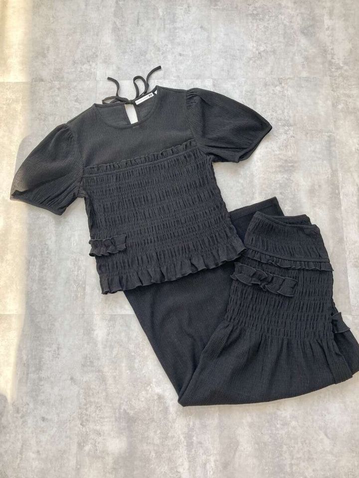 黒のシャーリングトップスとスカートのセットアップを平置き