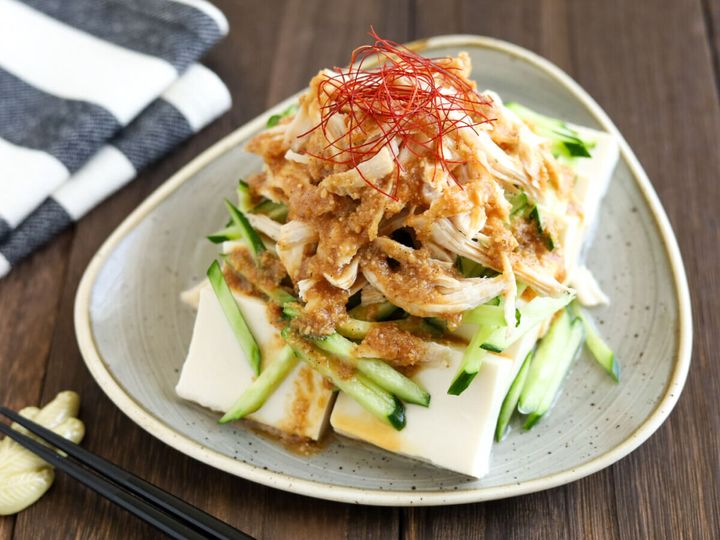 木製のテーブルに置かれた棒々鶏のせ冷奴に、箸と布巾が添えられた食卓の様子