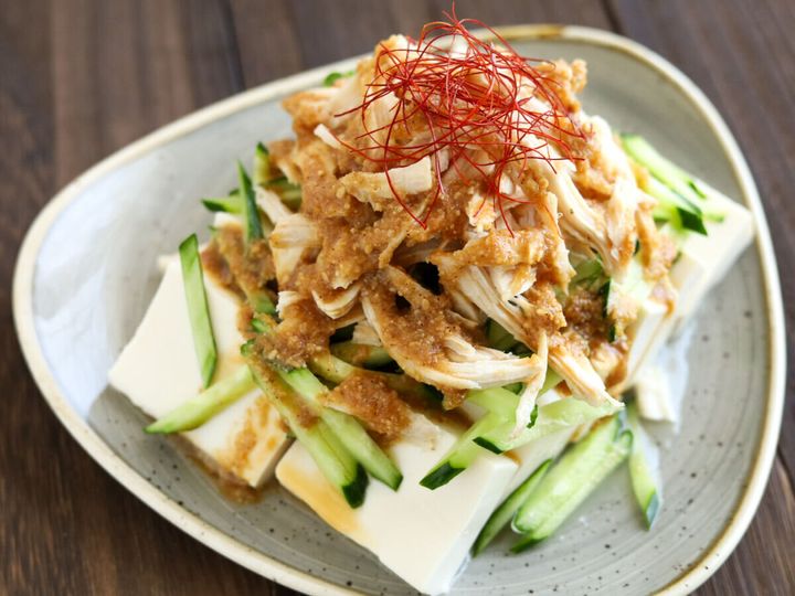 木製のテーブルに置かれた棒々鶏のせ冷奴が、斜め上から撮影された様子