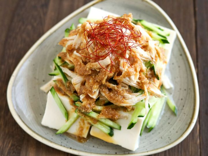 豆腐の上にきゅうり、ほぐした鶏肉、ごまだれ、糸唐辛子が盛り付けられた棒々鶏のせ冷奴