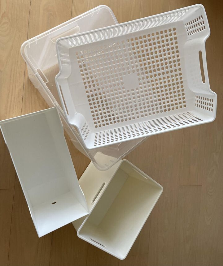 白いプラスチック製の収納ケースやバスケットが複数床に置かれている