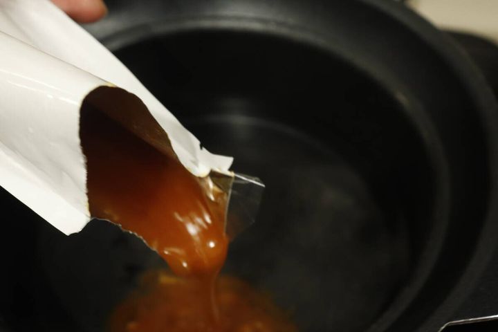 レトルトパウチから鍋にユッケジャンスープの素を注ぐ