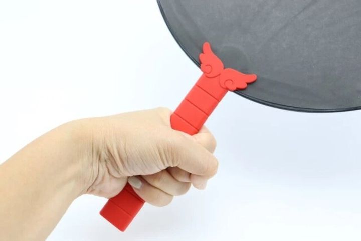 赤い羽デザインのうちわグリップを装着したうちわを持つ手元