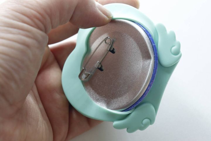 シリコン缶バッジスタンドに缶バッジを裏側から押し込んでいる手元