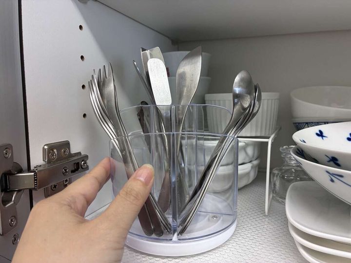 食器棚で回転式ペン立てを回しカトラリーを取り出している手元