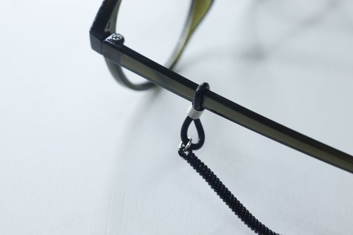 メガネのテンプルに黒いメガネストラップのゴムループを通している様子