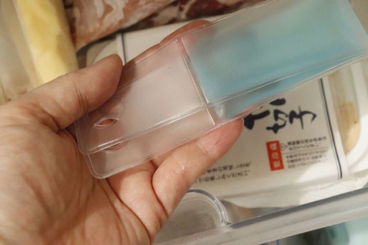 女性の手が、冷凍庫の引き出しにアイスパックを入れている