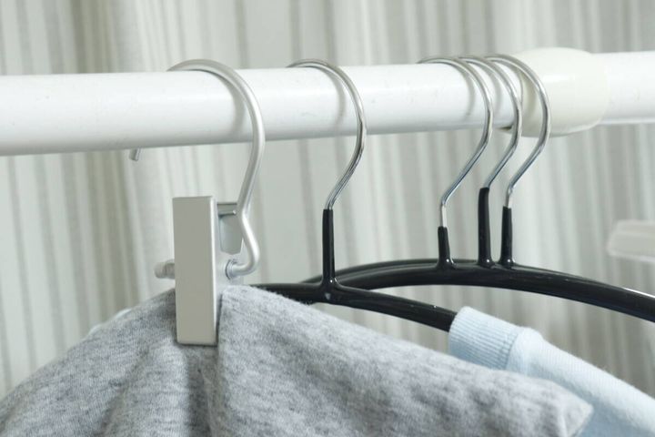 クローゼットのポールに吊るされたアルミフックピンチとスウェットパンツ、他のハンガー