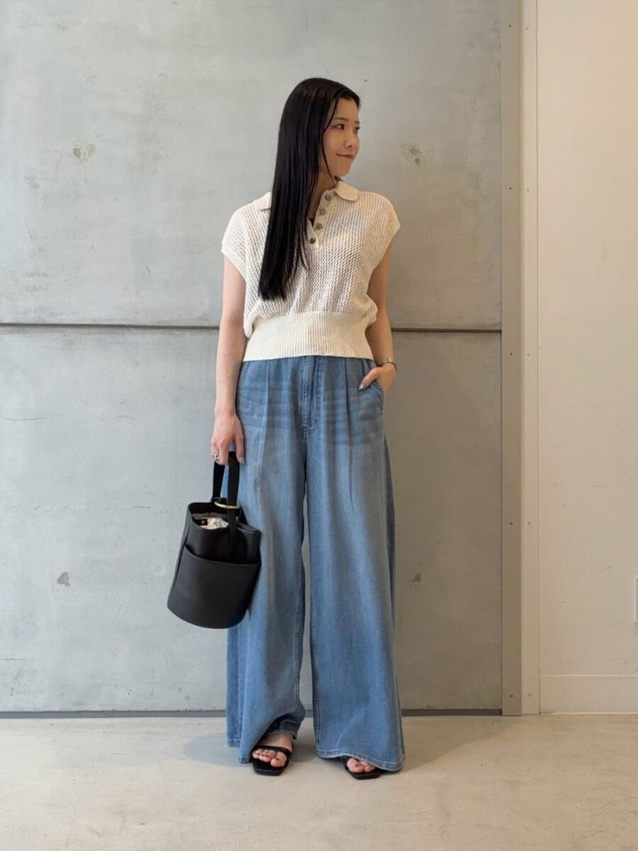 白のメッシュポロニットとワイドデニムを着用