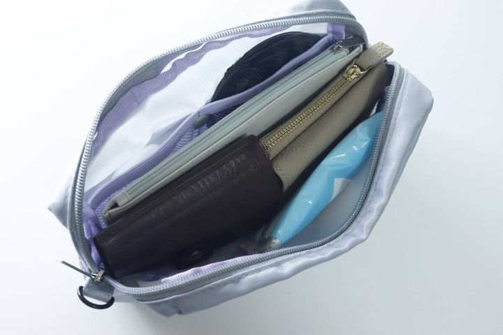 ポーチのメイン収納部に折りたたみ財布やフラグメントケースなどが入っている様子