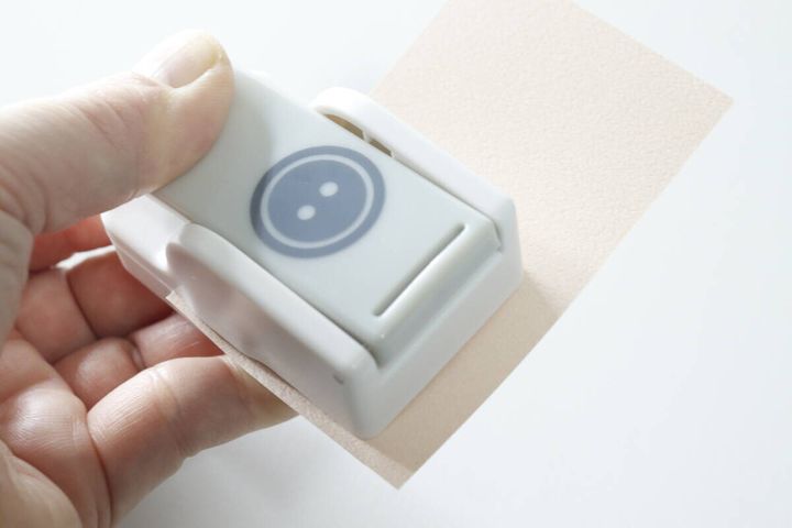クラフトパンチで画用紙をパンチしている手元