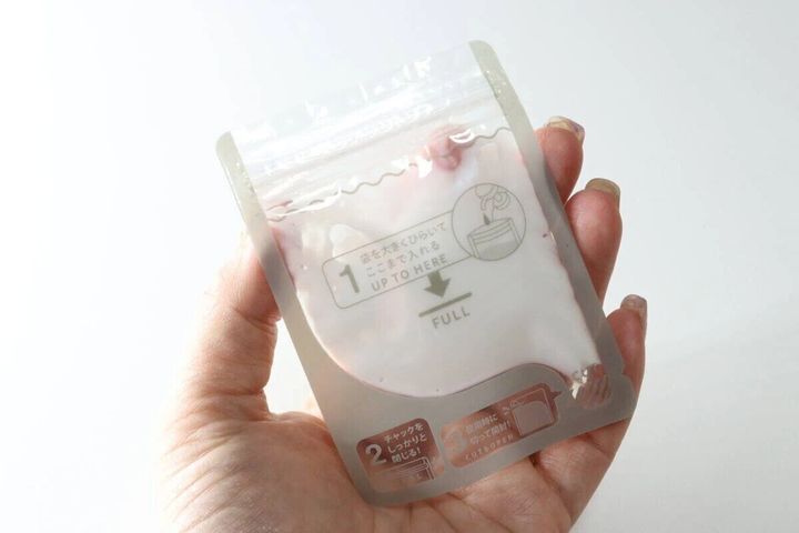 女性の手のひらに乗せた乳白色の詰め替えパウチ
