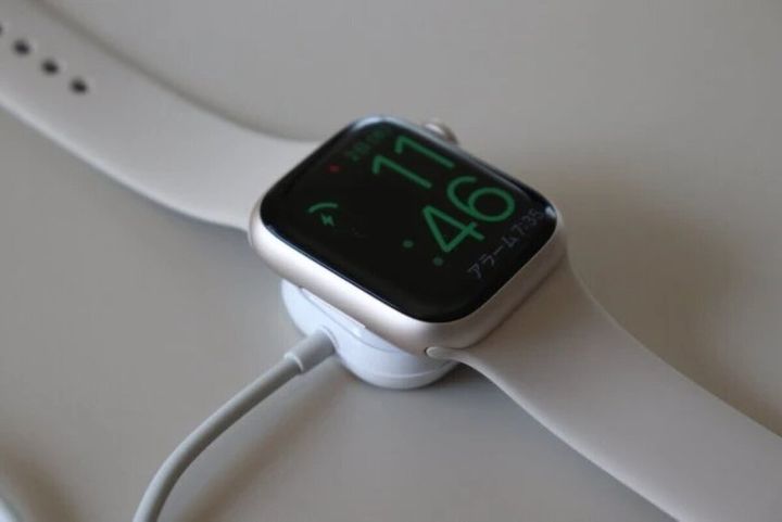 スマートウォッチが白い充電器に置かれ充電中の画面が表示されている