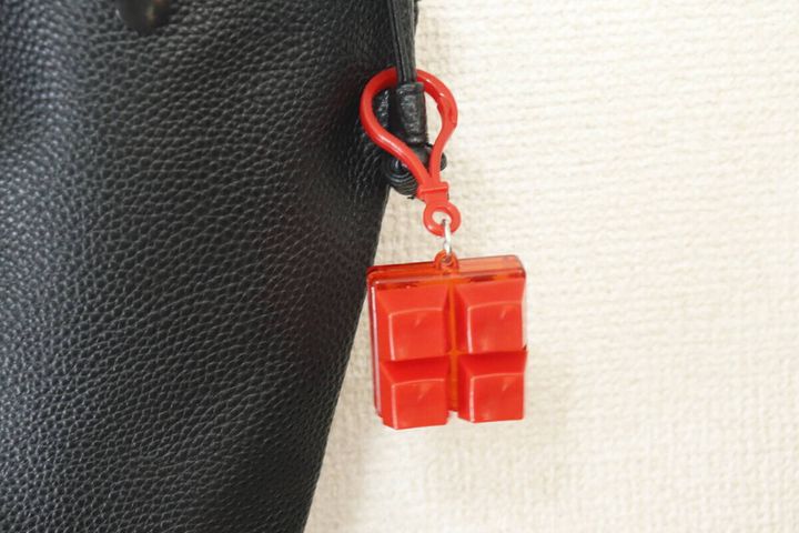 黒いバッグの持ち手に赤いカラーブロックキーホルダーがぶら下がっている