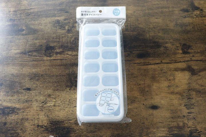 パッケージに入ったセリアの氷が取り出しやすい蓋付きアイストレーが木目のテーブルに置かれている