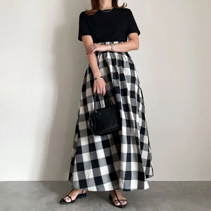 黒シアーTと白黒チェック柄スカートを着用した女性