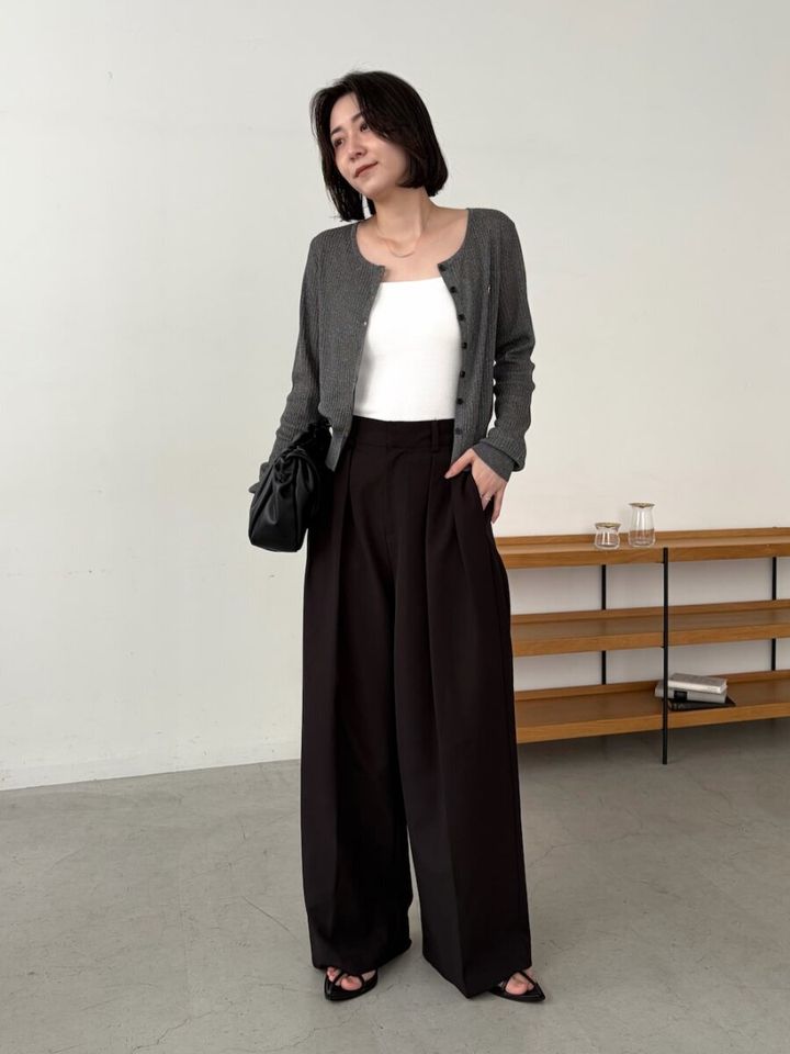 ショートヘアの女性がグレーカーデと黒ワイドパンツを着る