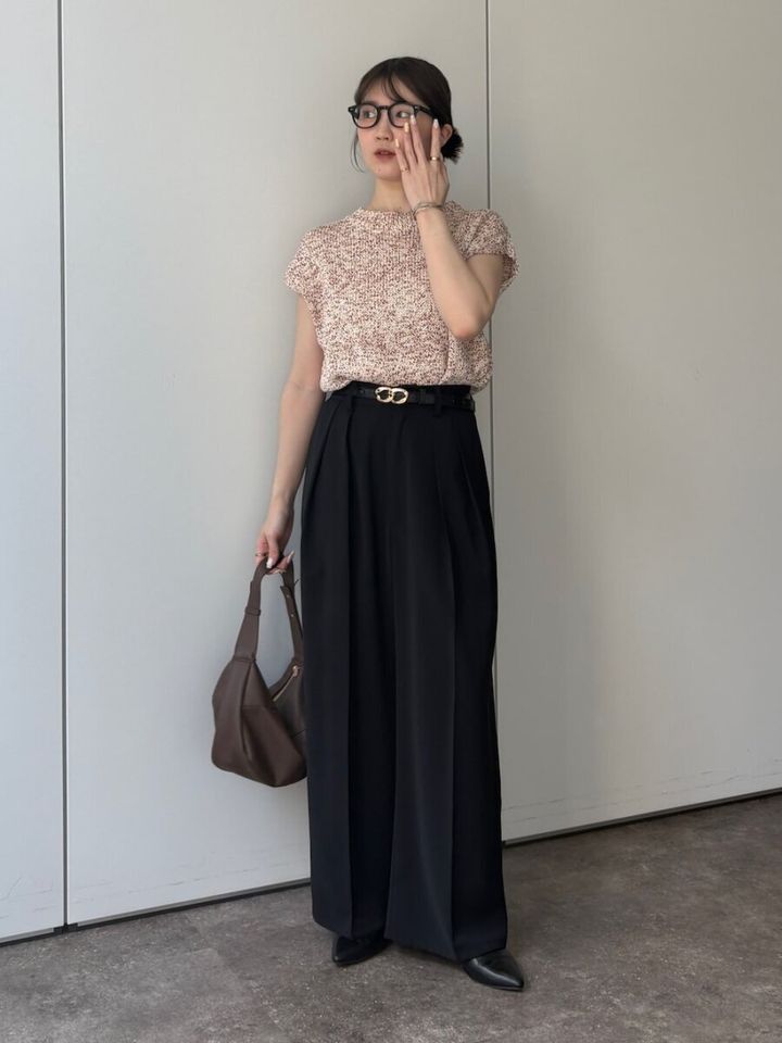 眼鏡の女性がピンクニットと黒ワイドパンツでポーズ