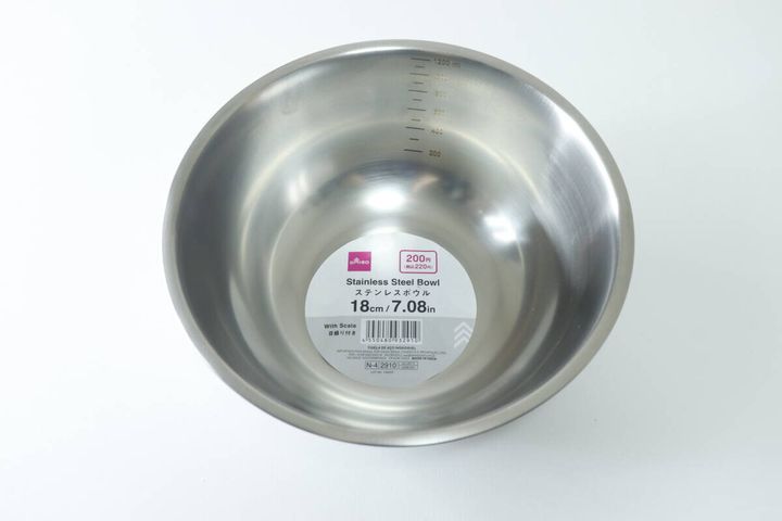 白い背景に置かれたダイソーのメモリ付きステンレスボウルと商品ラベル