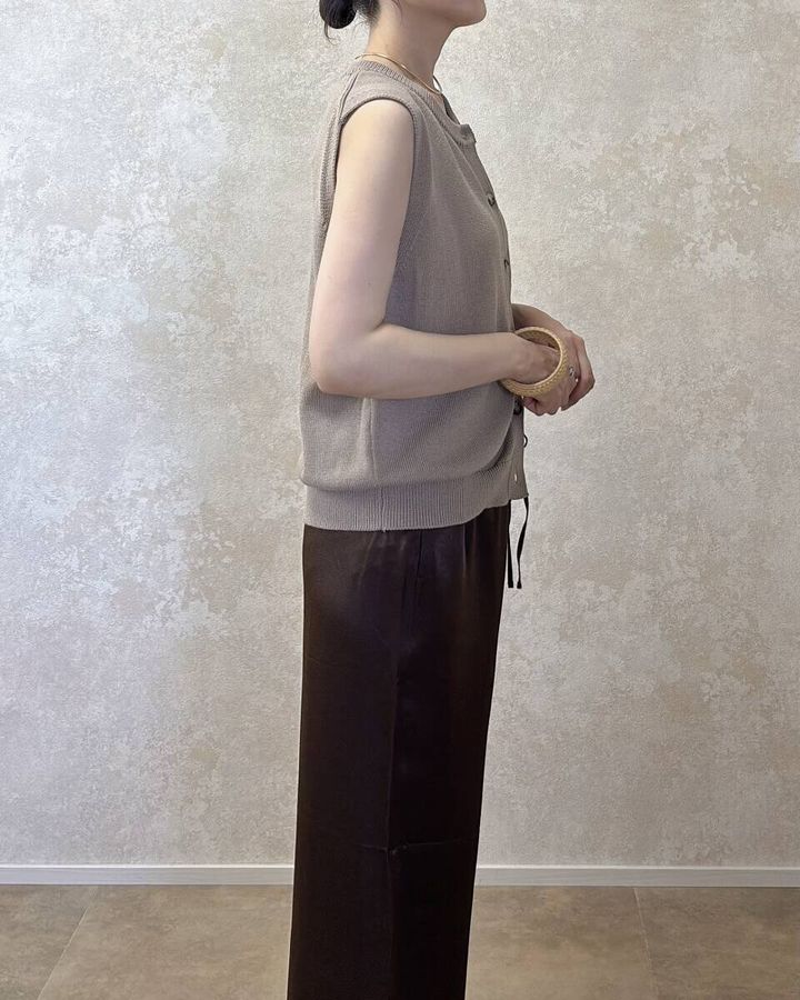 ベージュニットとブラウンパンツの女性が横向きに立つ