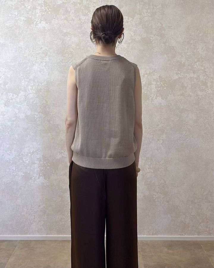 ベージュニットとブラウンパンツの女性が後ろ向きに立つ