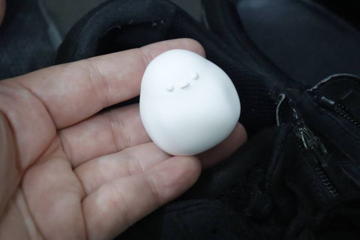 黒い靴の中に置かれたシマエナガ型珪藻土を指で持つ