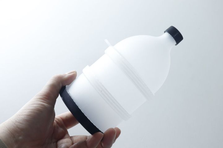 手が白いプロテイン容器を横向きに持ち、商品のサイズ感を示している