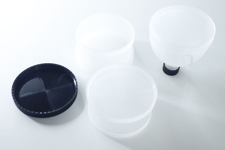 白い背景に、分解されたプロテイン容器の各パーツと黒い蓋