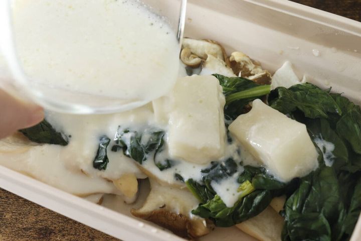 耐熱容器に入った具材と凍った牛乳キューブに白いソースをかけている