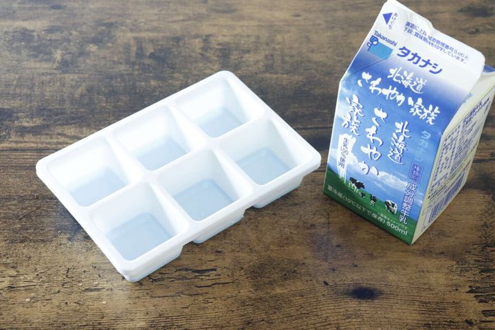 白い製氷皿とタカナシ牛乳パックが木製テーブルに置かれている