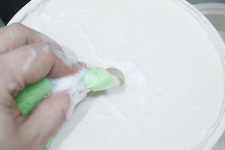泡立ったスポンジでスチーマーの蓋を洗う手