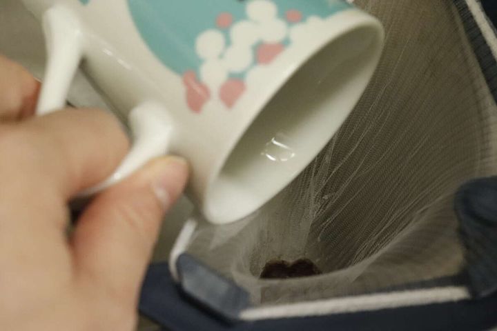 水切りネットにコーヒーかすをカップから捨てている手元