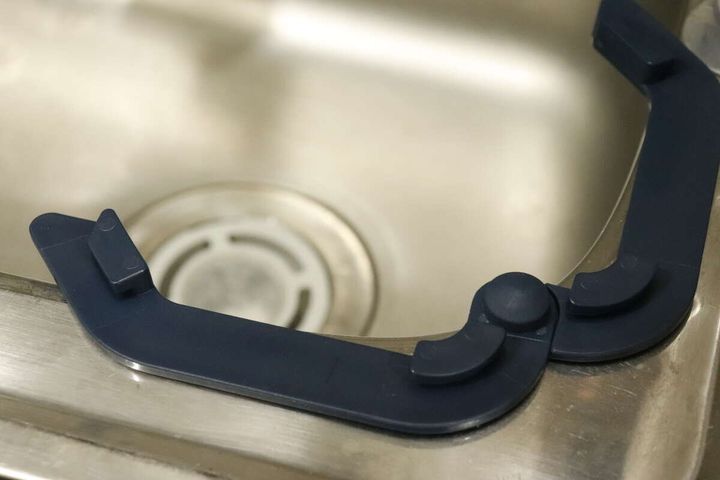 ステンレス製のシンクの縁に設置された紺色の水切りネットホルダー