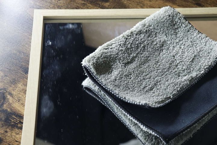 指紋や油分で汚れた鏡と、その横に置かれたクロス