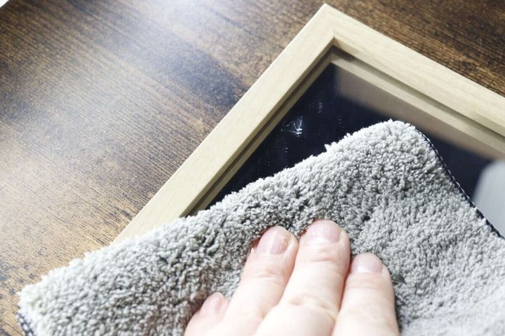 クロスのグレー面で汚れた鏡を拭いている手元