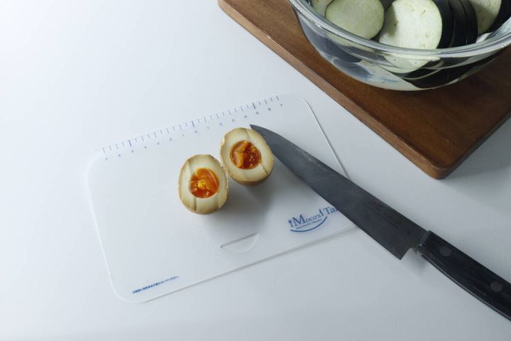 Sサイズのまな板に半分に切った味玉が2つと包丁が置かれている