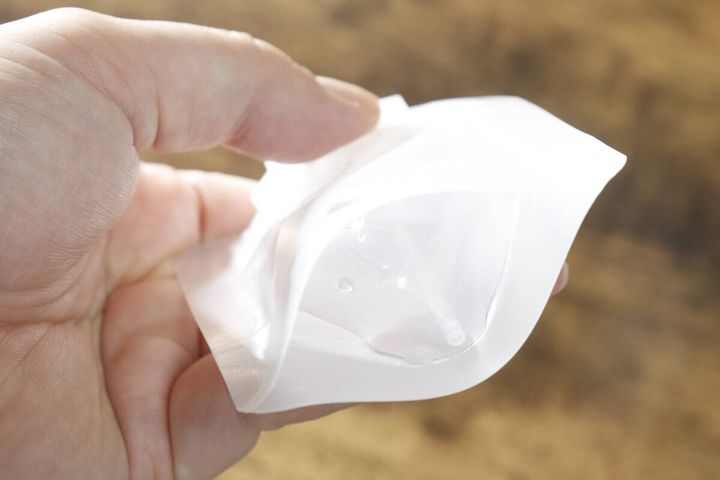 液体が入ったパウチ容器を指で押して柔らかさを確認