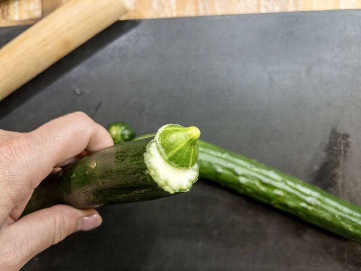 手で持ったきゅうりの切り口にヘタを押し当ててアク抜きしている