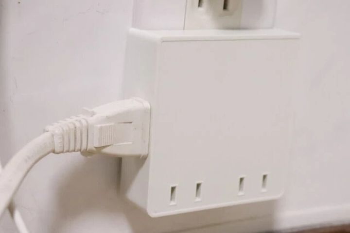白い壁のコンセントに差し込まれた白いスクエア型の4個口電源タップ