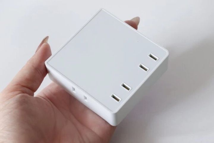 女性の手のひらに乗せられた白いスクエア型の4個口電源タップ