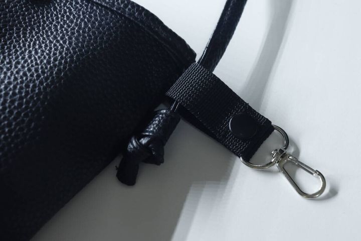 黒い細いショルダーベルトのバッグに小物ホルダーを取り付けている