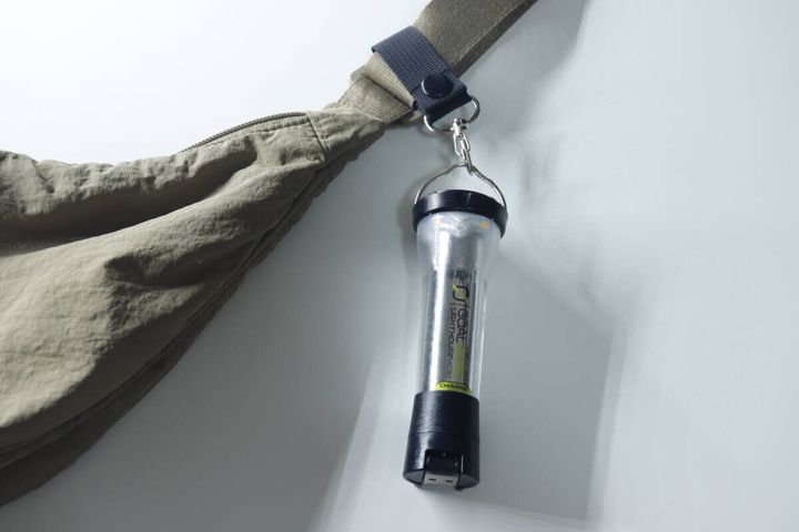 バッグのベルトに取り付けた小物ホルダーに懐中電灯を吊り下げている