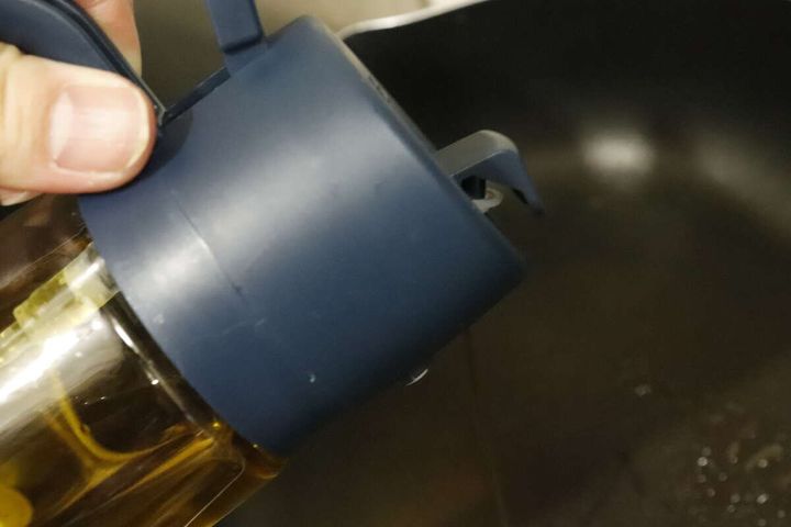 フライパンにオイルを注いでいる手元