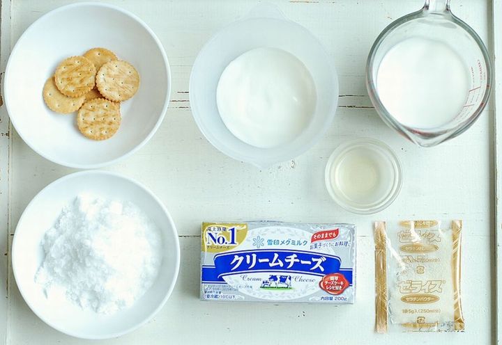 レアチーズケーキの材料が白い木目のテーブルに並べられている俯瞰写真